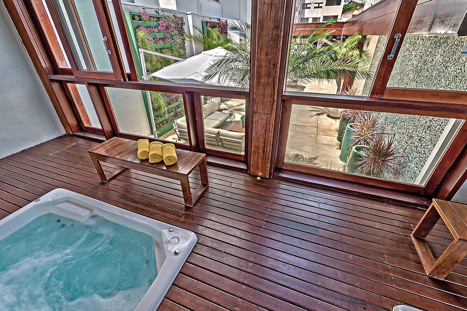 A wooden deck with a hot tub and a small table with towels.