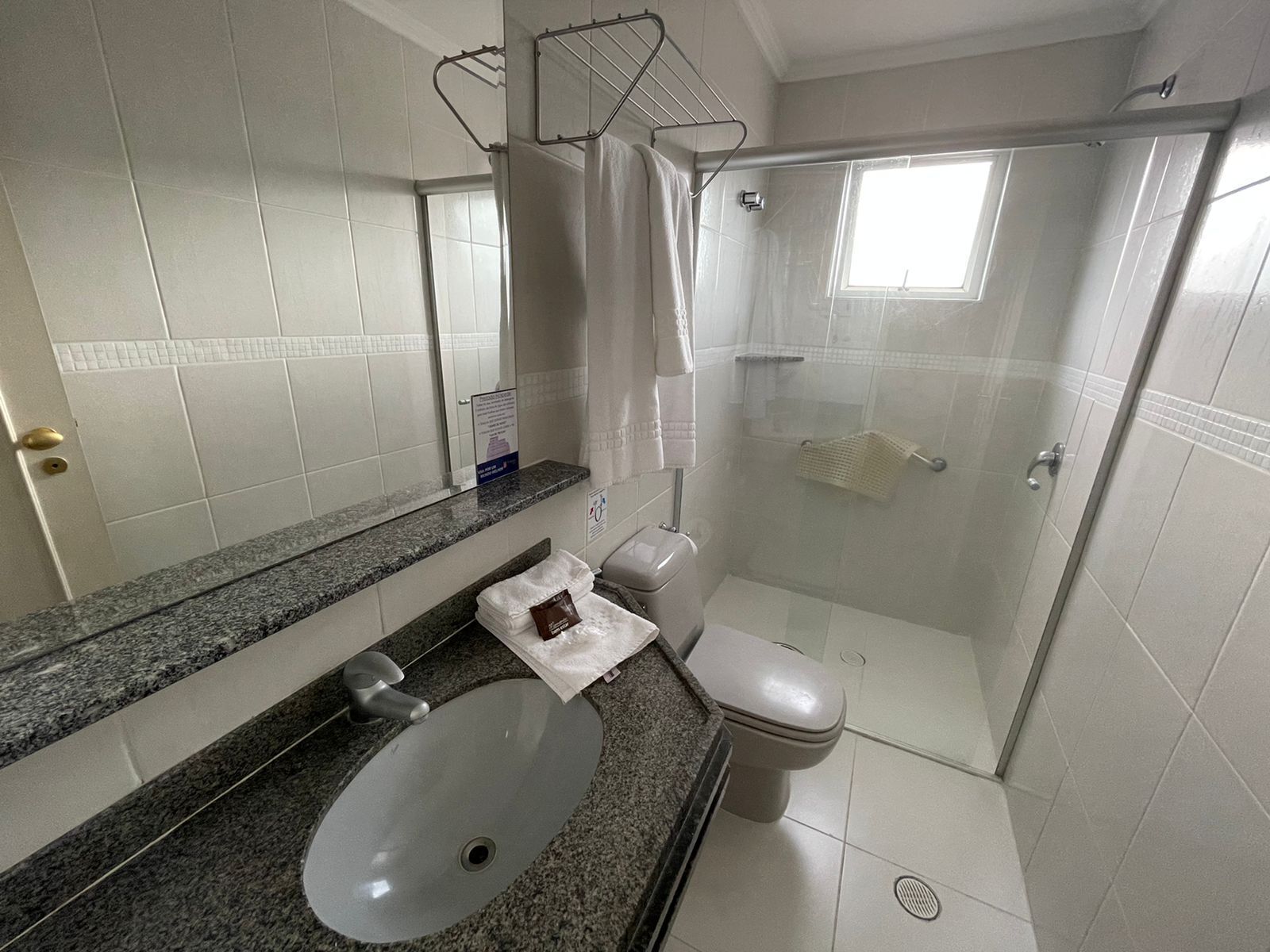 A modern bathroom with a granite countertop, a sink, a toilet, and a glass-enclosed shower.