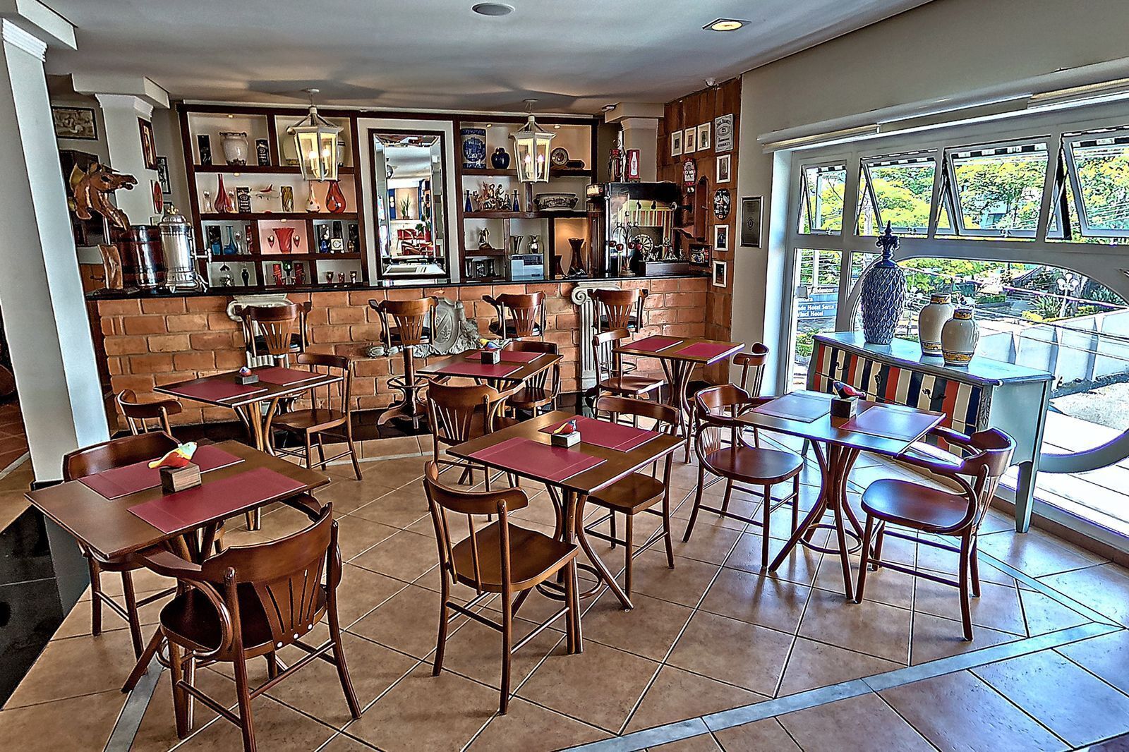 Un restaurant avec de nombreuses tables et chaises en bois, un mur en briques et des étagères remplies de divers objets.