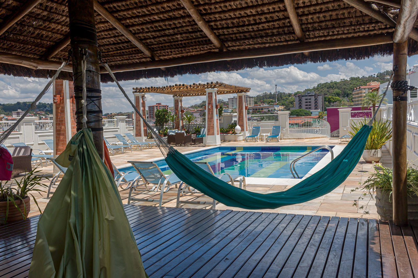 Un espace piscine aménagé sur le toit, avec un hamac, des chaises longues et une pergola.