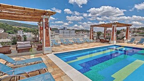 Un área de piscina en la azotea con sillones de descanso y una pérgola.