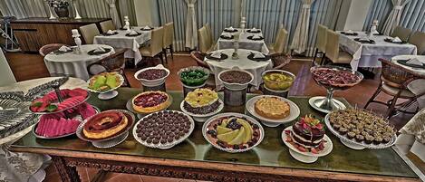 Un espace repas avec plusieurs tables dressées pour un buffet, proposant une variété de desserts et de plats.