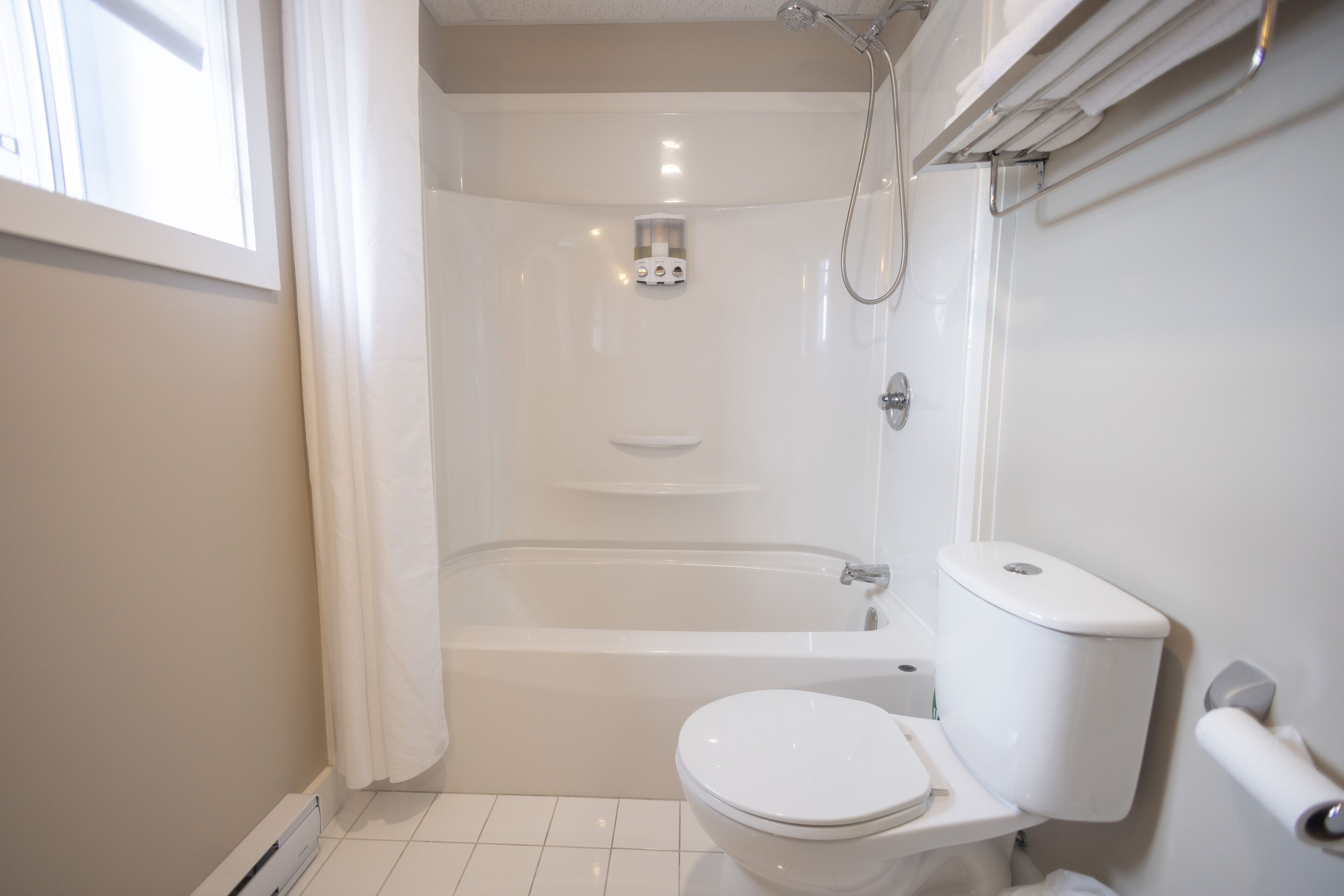 A modern bathroom with a bathtub, toilet, and shower.