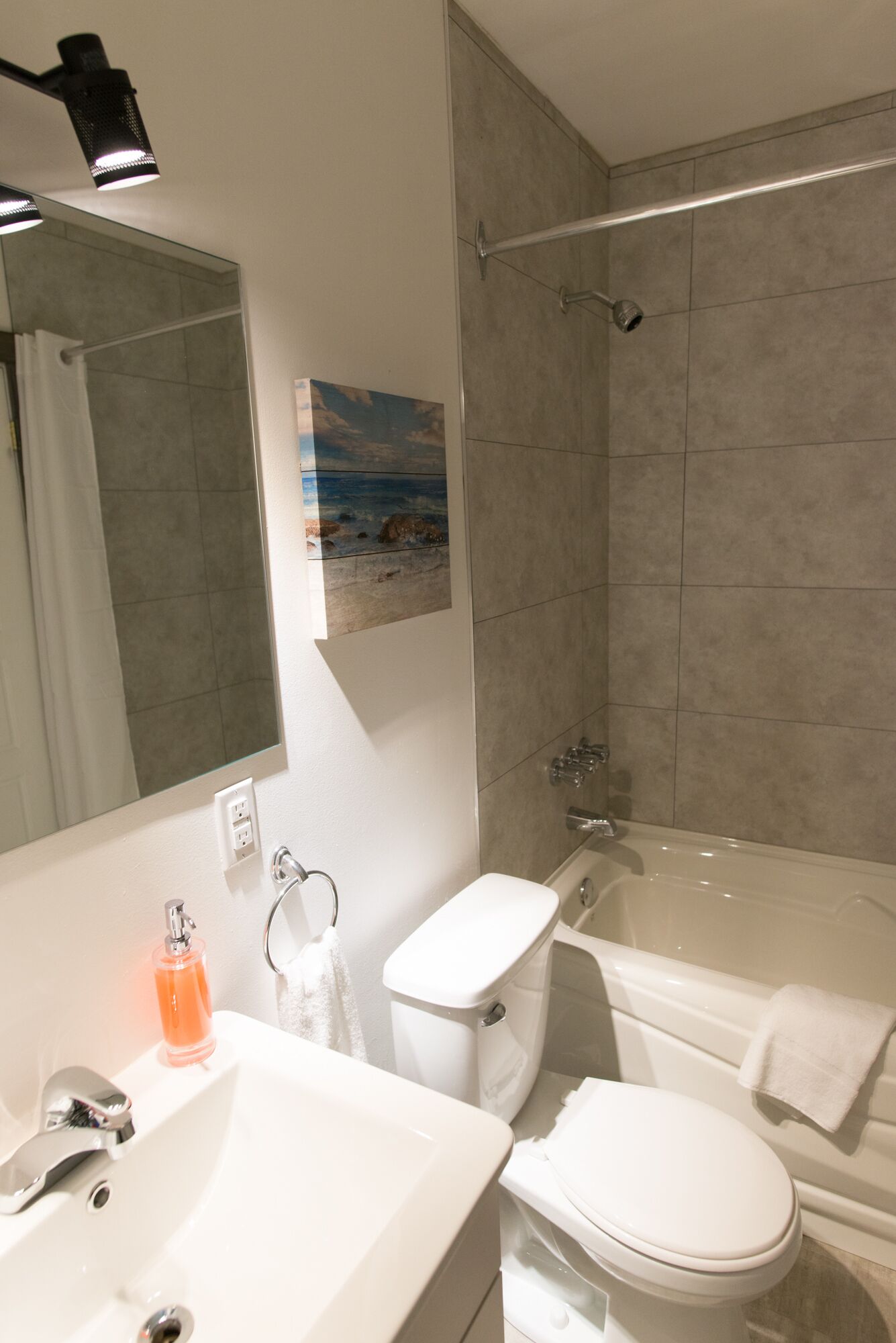 A modern bathroom with a sink, toilet, bathtub, and shower.
