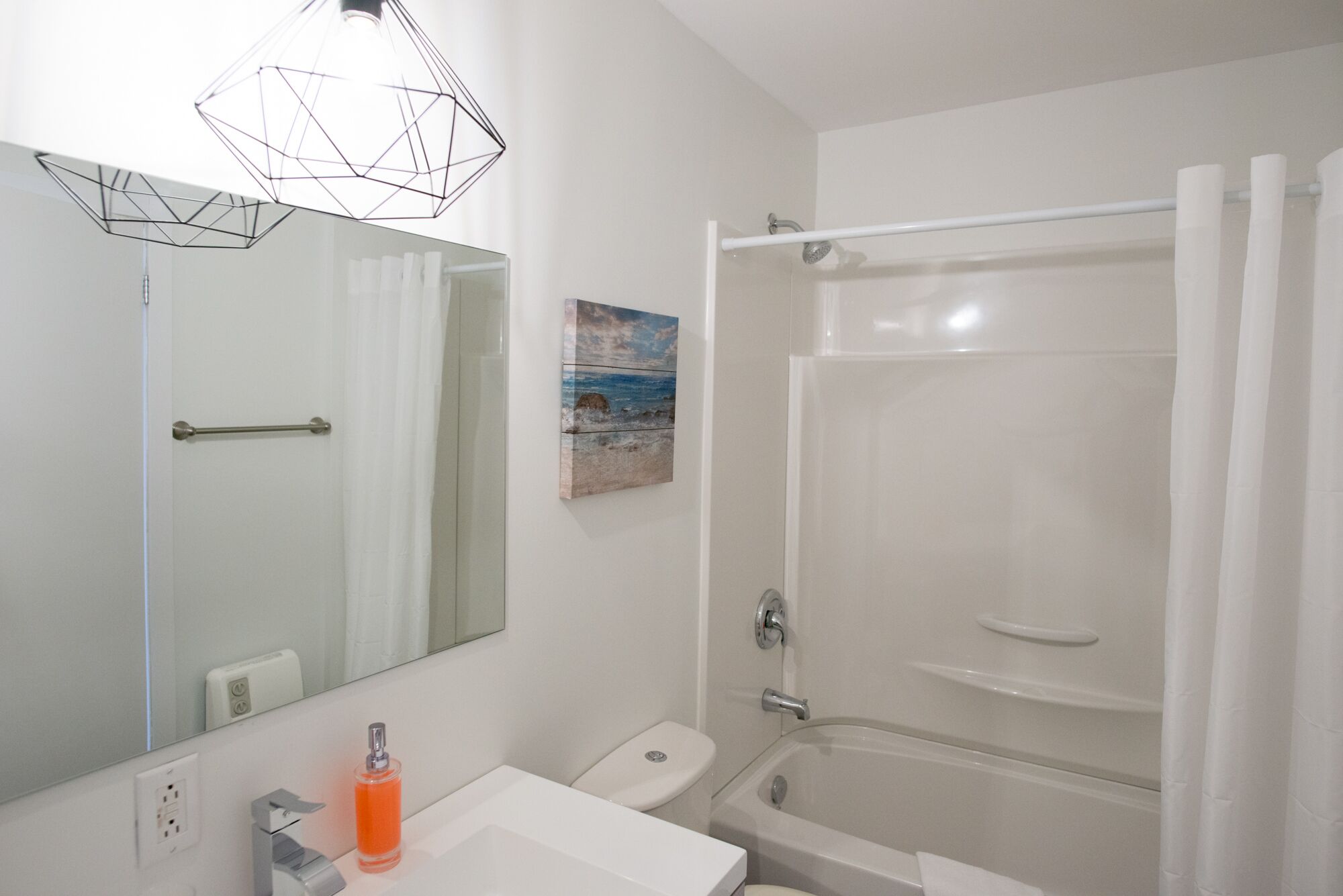 Ein Badezimmer mit weißem Waschbecken, Toilette, Badewanne und Duschvorhang.