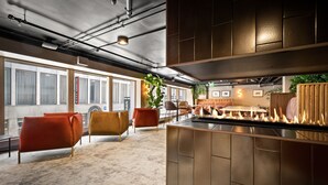 Un intérieur moderne avec un espace bar, des sièges avec des chaises orange et une grande plante.