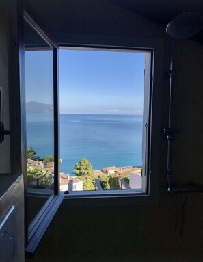 Une pièce dotée d’une grande fenêtre donnant sur la mer et sur une chaîne de montagnes lointaine.