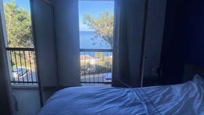 A bedroom with a bed, a window, and a door. - Large apartment with sea/village view 200m from the beach (Saint-Florent)