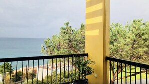 A balcony with a yellow wall, a view of the sea, and some greenery. - Large apartment with sea/village view 200m from the beach (Saint-Florent)