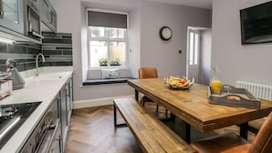 Cocina moderna con una mesa de comedor de madera, bancos y una ventana con vistas al exterior.