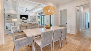 A spacious dining area with a large table, wicker chairs, and a hanging light fixture. - New Build in desirable Ocean Park community (Kiawah Island)