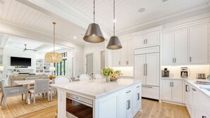 A modern kitchen with white cabinetry, a large island, and pendant lighting. - New Build in desirable Ocean Park community (Kiawah Island)