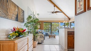 A spacious living area with a large window, a ceiling fan, a dining area, and a kitchen.