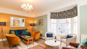 A living room with a sofa, two armchairs, a coffee table, and a chandelier. - Seaside House (Weymouth)