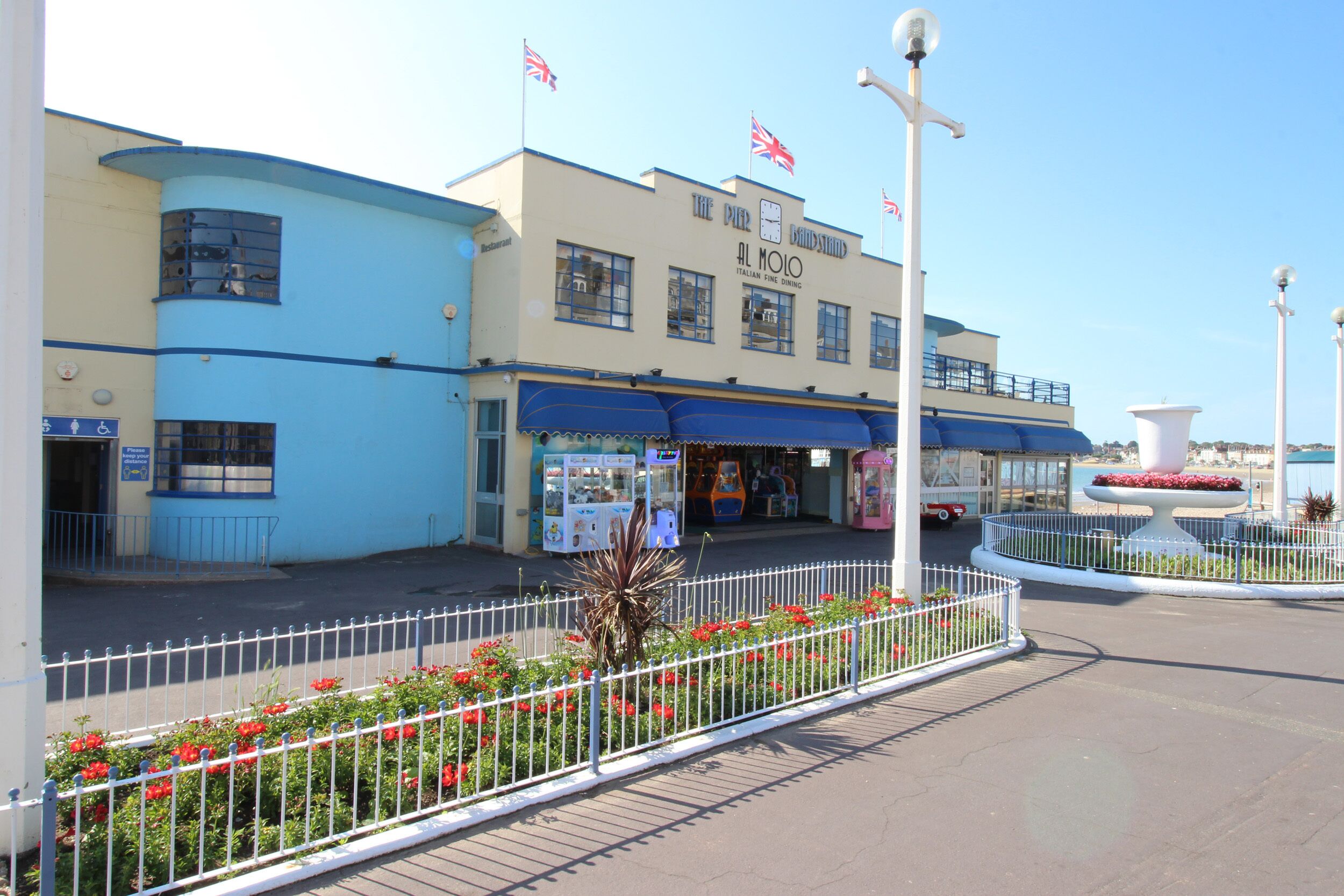 A building with a blue facade, a clock, and flags.
