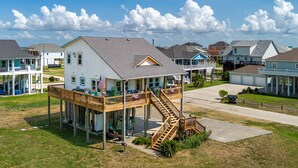 Ein zweistöckiges Haus mit überdachter Veranda und einer Holztreppe.