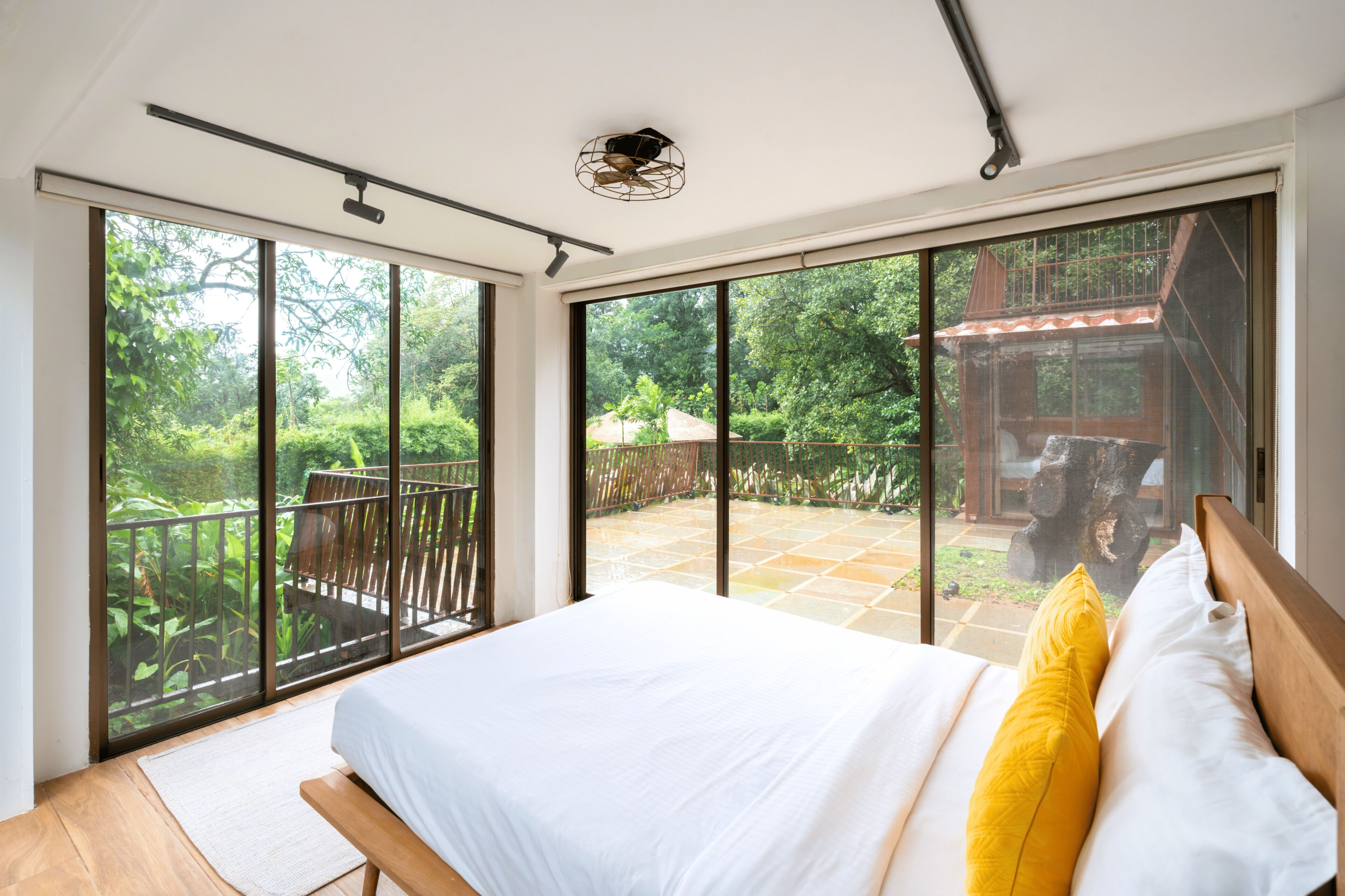 A bedroom with a large bed, a view of a wooden deck, and a balcony.
