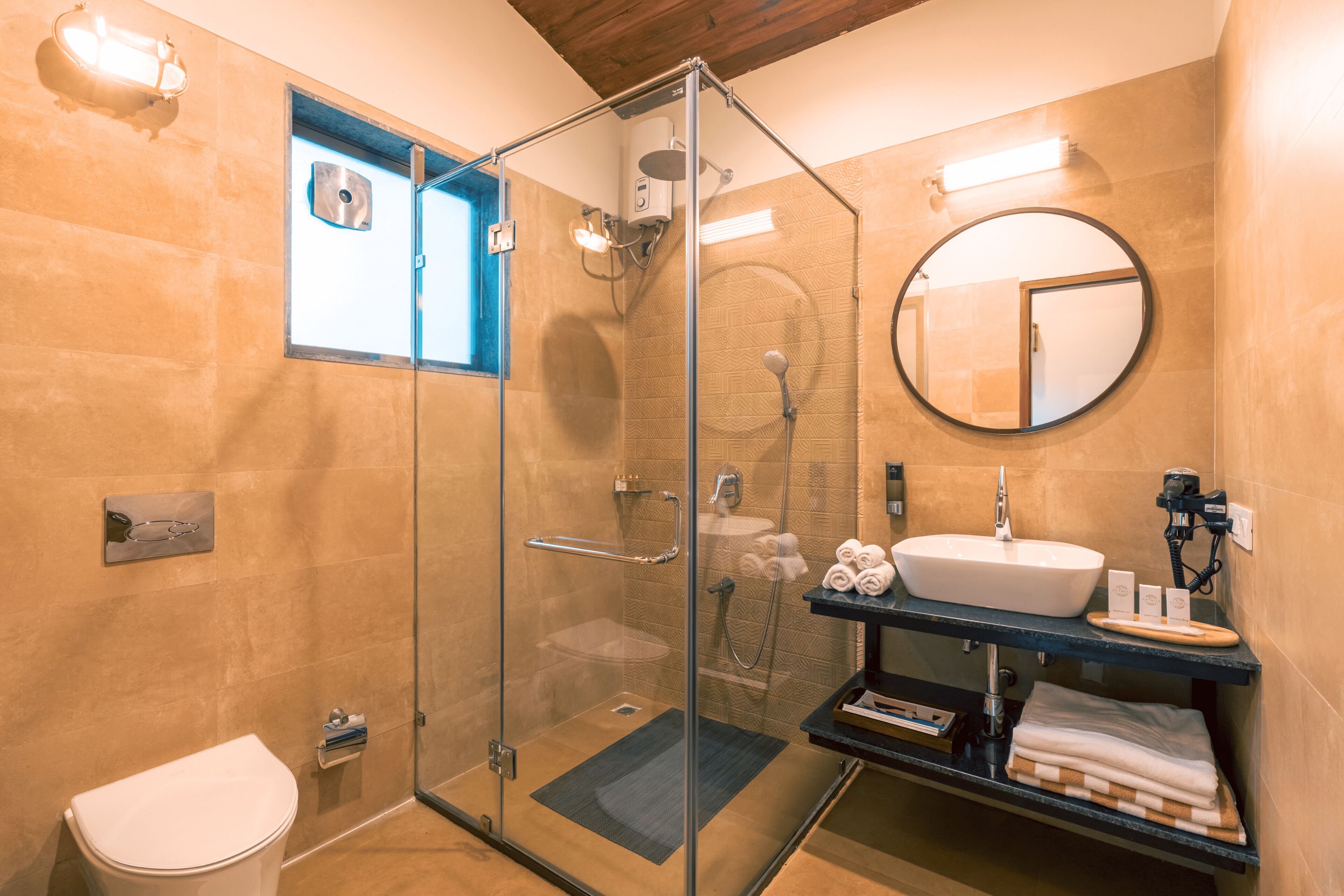 Ein modernes Badezimmer mit einer gläsernen Duschkabine, einem weißen Waschbecken und einem runden Spiegel.