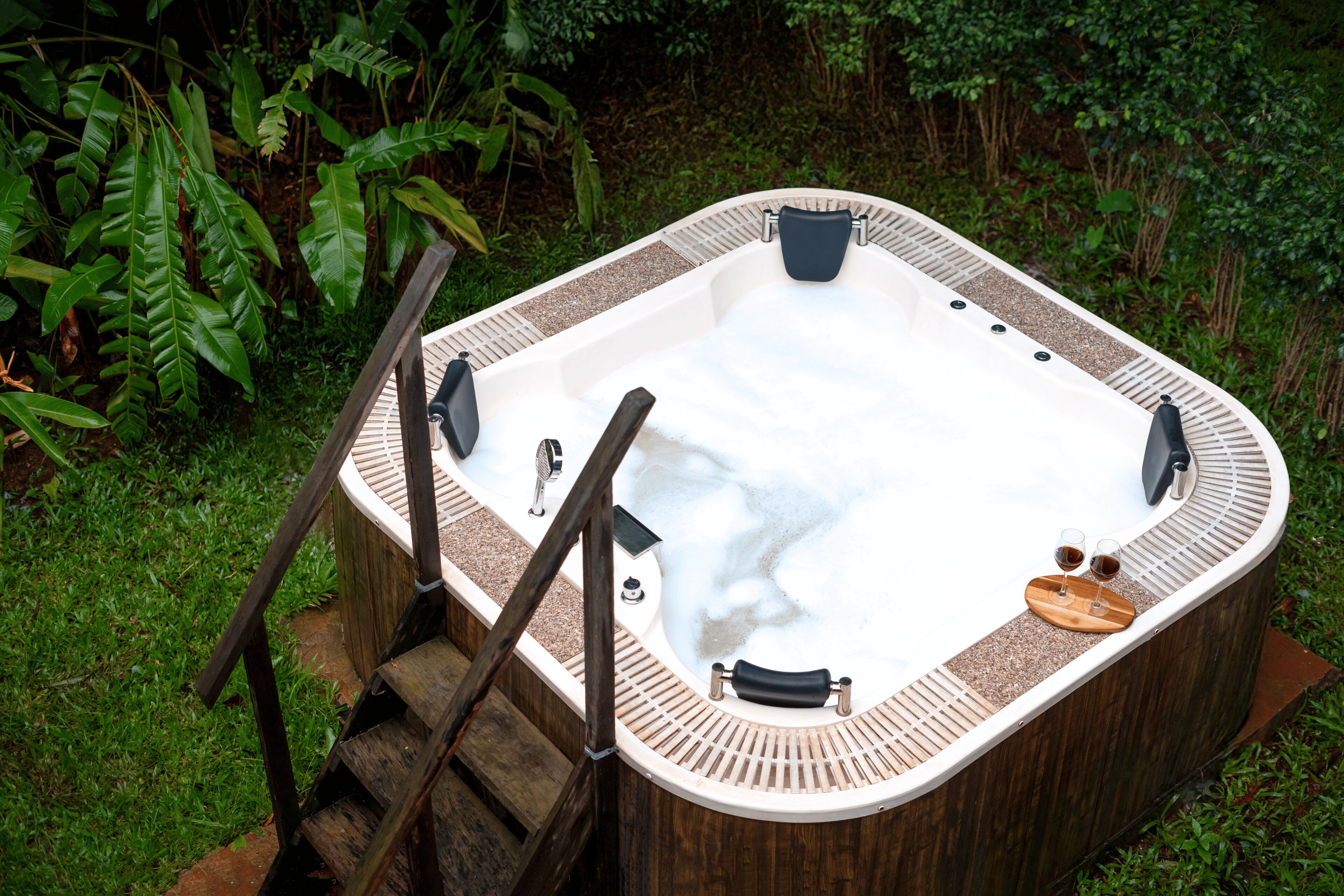 A hot tub with a wooden exterior, built-in seating, and a wooden ladder leading to the entrance.
