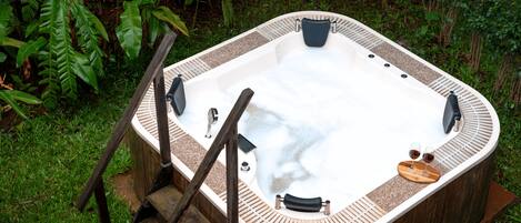 A hot tub with a wooden exterior, built-in seating, and a wooden ladder leading to the entrance.