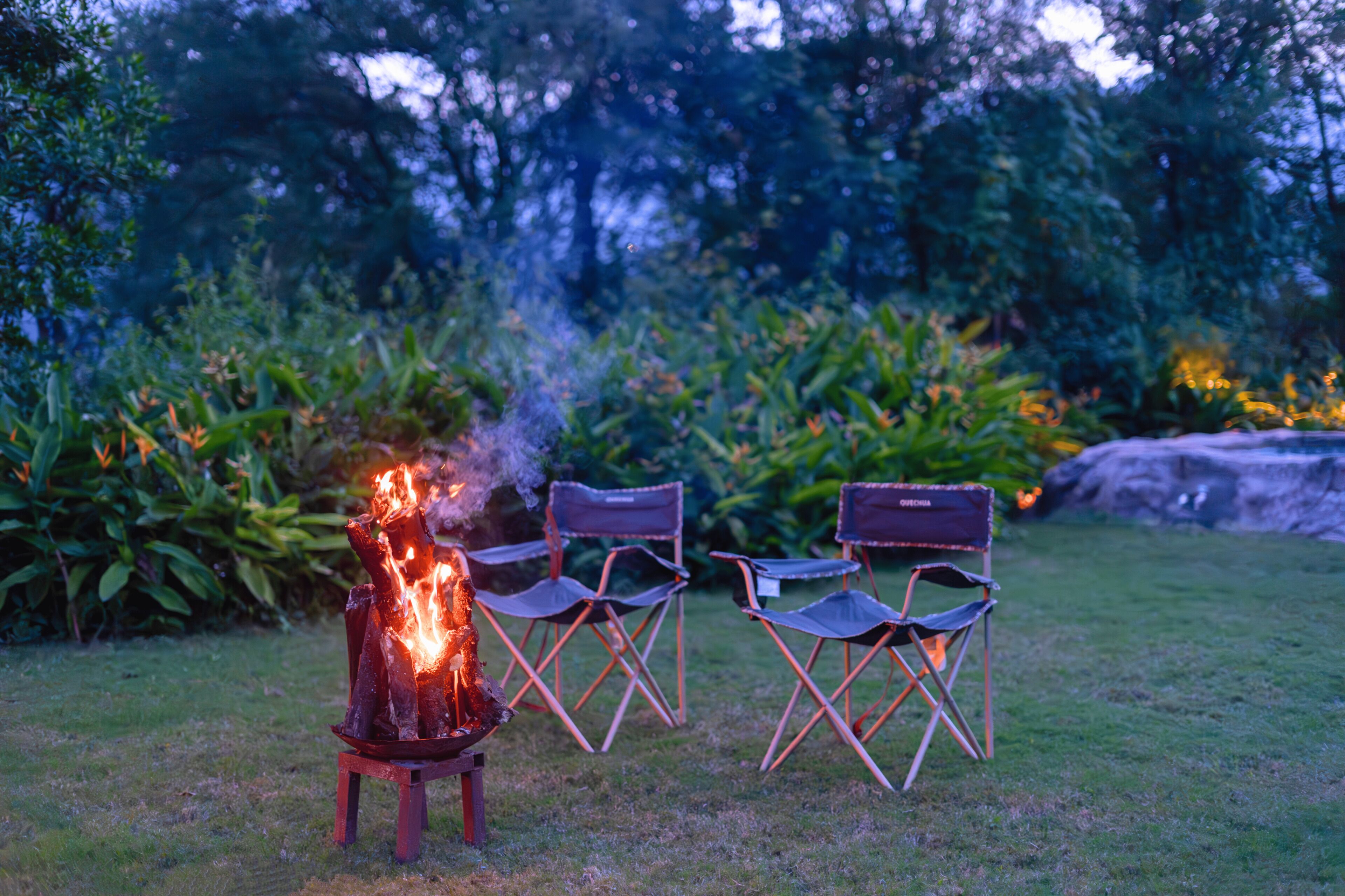 A campfire with chairs arranged around it in an outdoor setting.