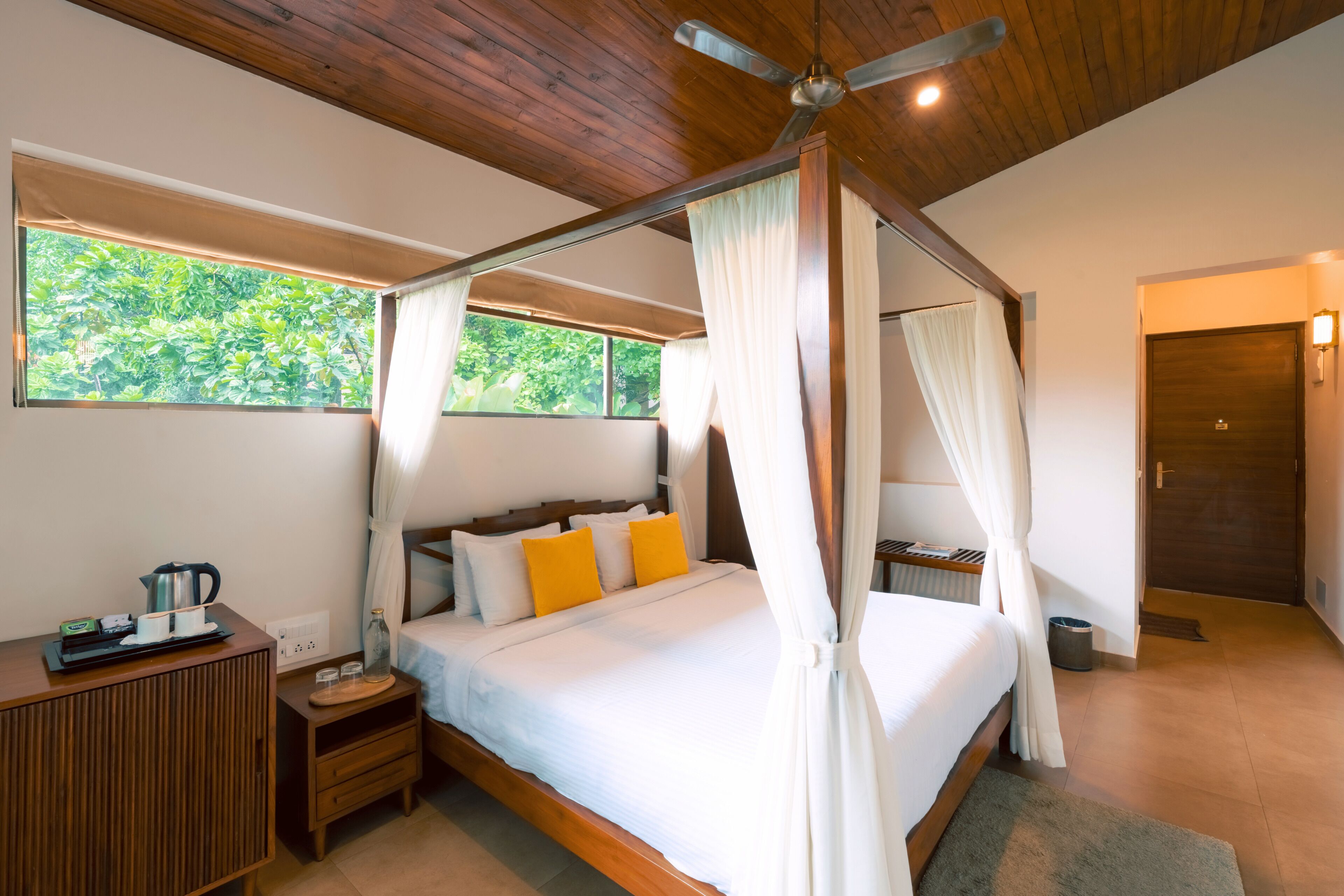 A bedroom with a four-poster bed, wooden headboard, and a ceiling fan.