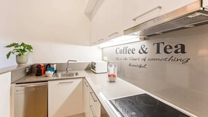 A modern kitchen with a stainless steel sink, a coffee machine, and a tea station.