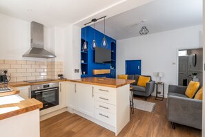 A modern kitchen with a built-in oven, a stainless steel range hood, and a wooden countertop.