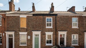Une rangée de maisons mitoyennes aux façades en briques, aux fenêtres à cadre blanc et à la porte verte.