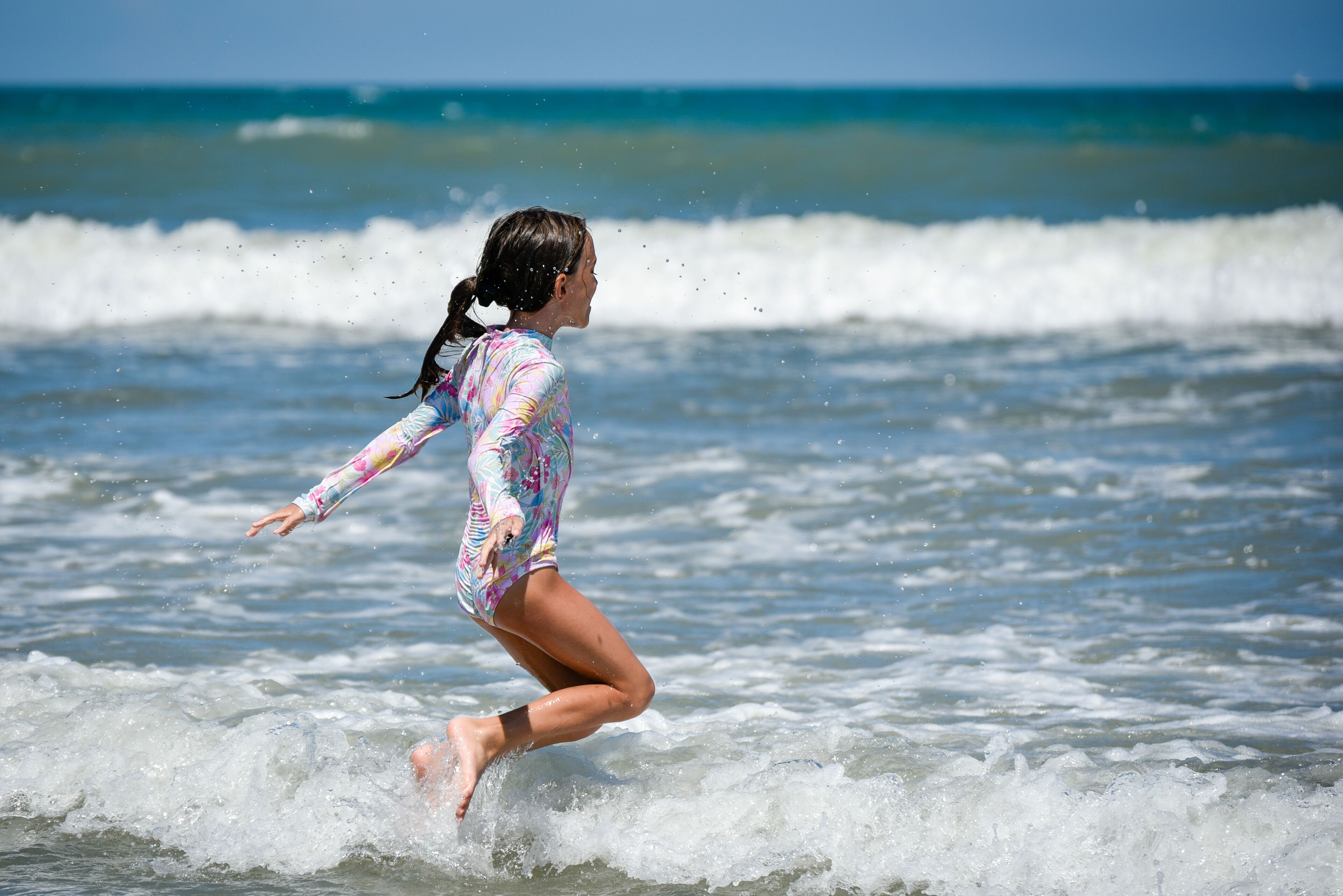 A person in a colorful swimsuit running through the water.