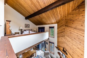 Quarto em estilo loft com teto de madeira, varanda, escrivaninha e cadeira.