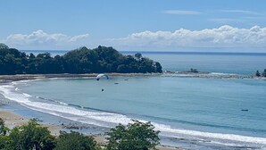 A coastal landscape with a beach, ocean, and a forested island.