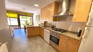 A modern kitchen with wooden cabinets, a stainless steel range hood, a built-in oven, and a granite countertop. - Léscala house, communal swimming pool and private garden (L'Escala)