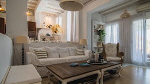 A spacious living room with a white sofa, a wooden coffee table, and a wicker armchair. -  6Bedroom Villa with private pool, located in Kalafatis, Mykonos (Καλαφάτη, Μύκονος)