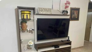 Un meuble de divertissement moderne, doté d’un téléviseur à écran plat, d’objets décoratifs et d’une enseigne portant l’inscription « HOME ».