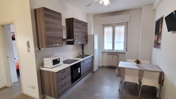 A modern kitchen with a built-in microwave, a sink, and a dining area with a table and chairs. - Residence Bonomelli apt. no. 18 two-room apartment (Bergamo)