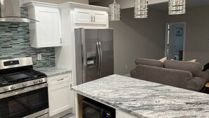 A modern kitchen with white cabinetry, stainless steel appliances, a granite countertop, and pendant lighting. - Modern and Chic in German & Merion Village Area (Columbus)
