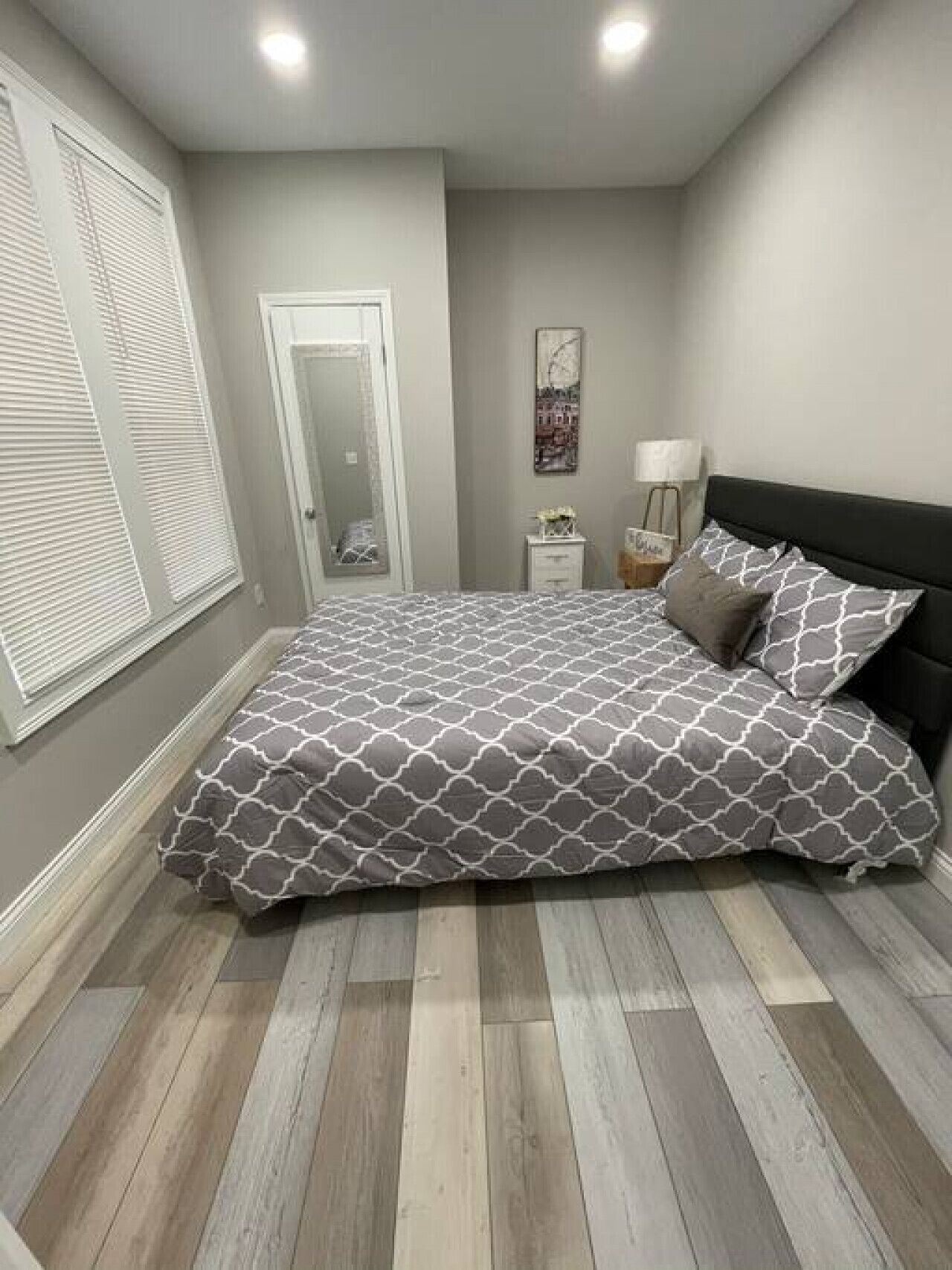 A bedroom with a bed, a nightstand, a lamp, and a door.