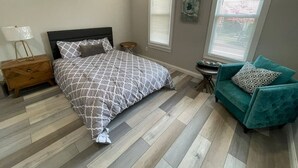 A bedroom with a bed, a nightstand, a chair, and a window. - Modern and Chic in German & Merion Village Area (Columbus)