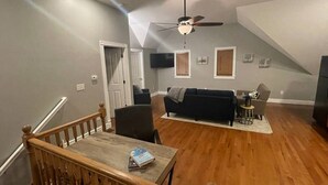 A spacious living area with a wooden dining table, a dark-colored sofa, and a ceiling fan. - Cozy and Modern Short North Carriage House (Columbus)