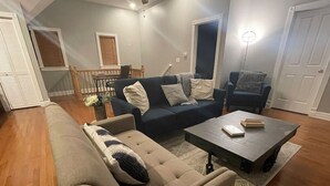 A living room with a beige sectional sofa, a dark blue sofa, and a coffee table. There is a dining area in the background with a wooden table and chairs. - Cozy and Modern Short North Carriage House (Columbus)