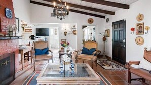 A living room with a chandelier, two armchairs, a coffee table, and a fireplace. - 3BR w/ Pool + Outdoor Fireplace | Near Downtown (Palm Springs)