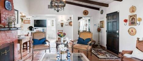 A living room with a chandelier, two armchairs, a coffee table, and a fireplace.