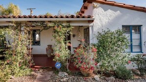 A house with a white exterior, a tiled roof, and a porch with climbing plants. - 3BR w/ Pool + Outdoor Fireplace | Near Downtown (Palm Springs)