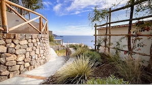 Un mur de pierre, une rambarde en bois et une vue sur la mer.