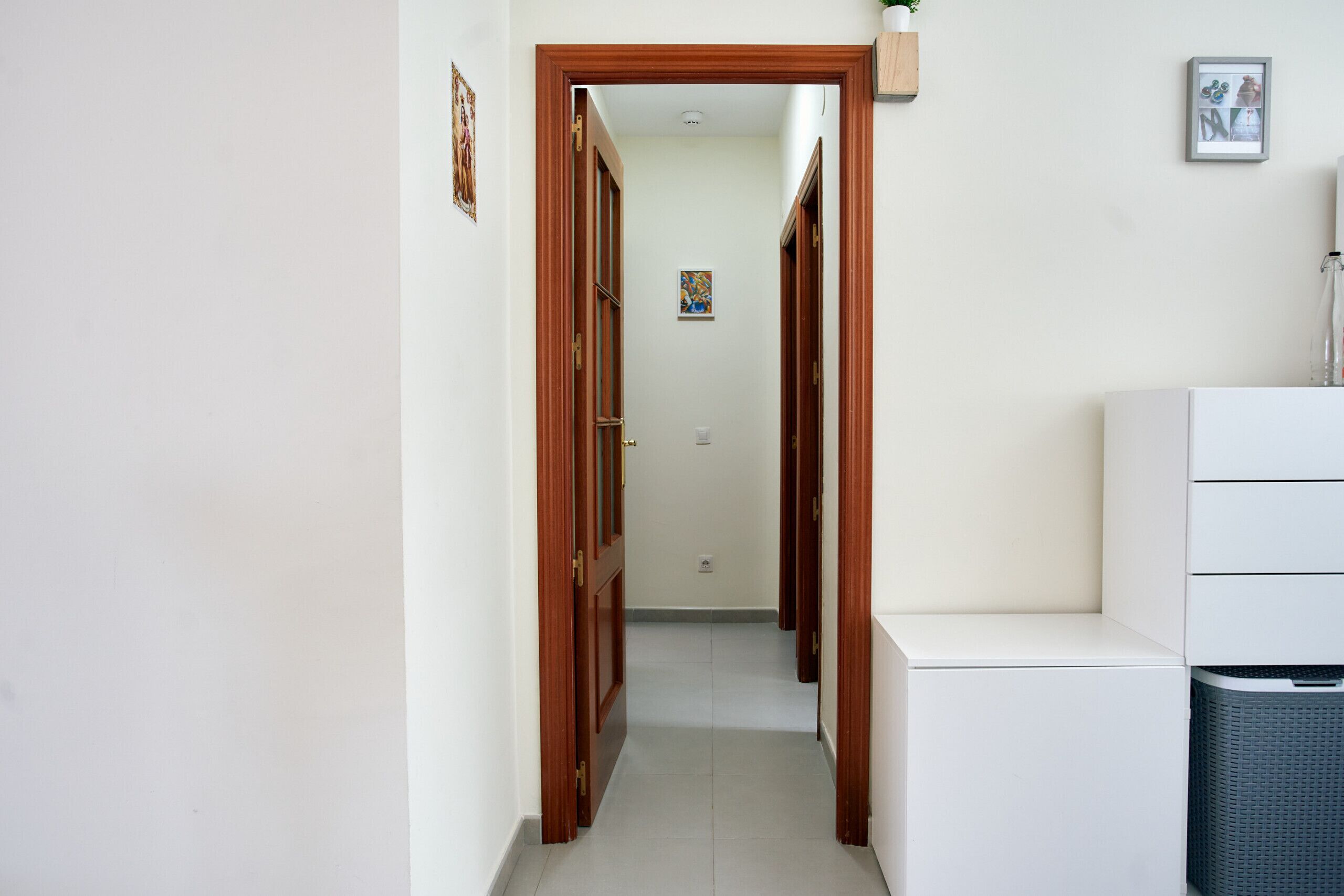 A narrow hallway with wooden doors and a white cabinet on the right.