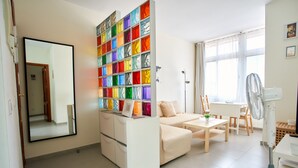A modern living room with a sofa, a dining table, and a colorful glass block wall.