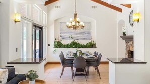 A dining area with a chandelier, a painting, and a stone fireplace. - Spacious Luxury Retreat Sleeps 20 with Jacuzzi (Fallbrook)