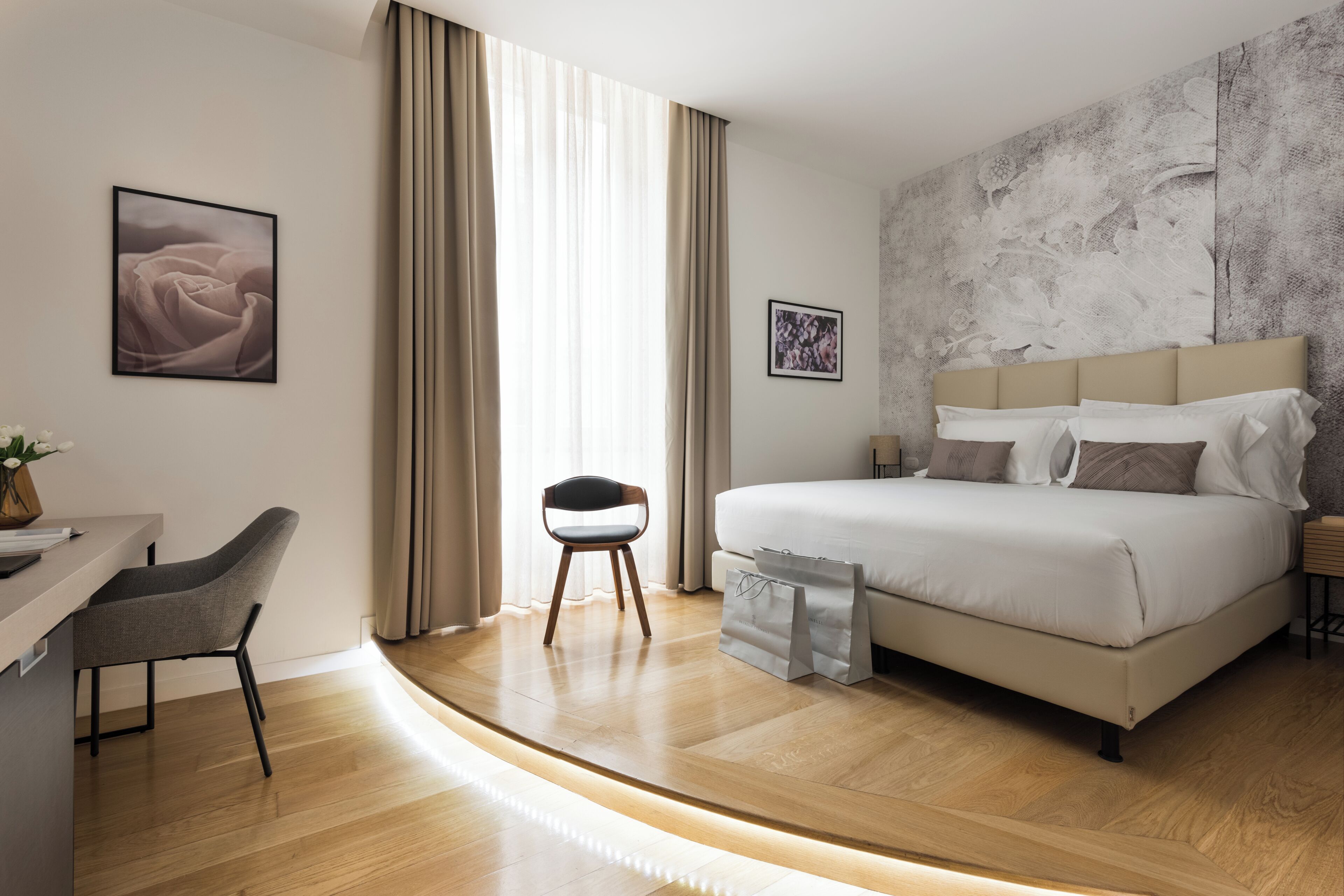 A modern hotel room with a bed, a desk, and a chair.