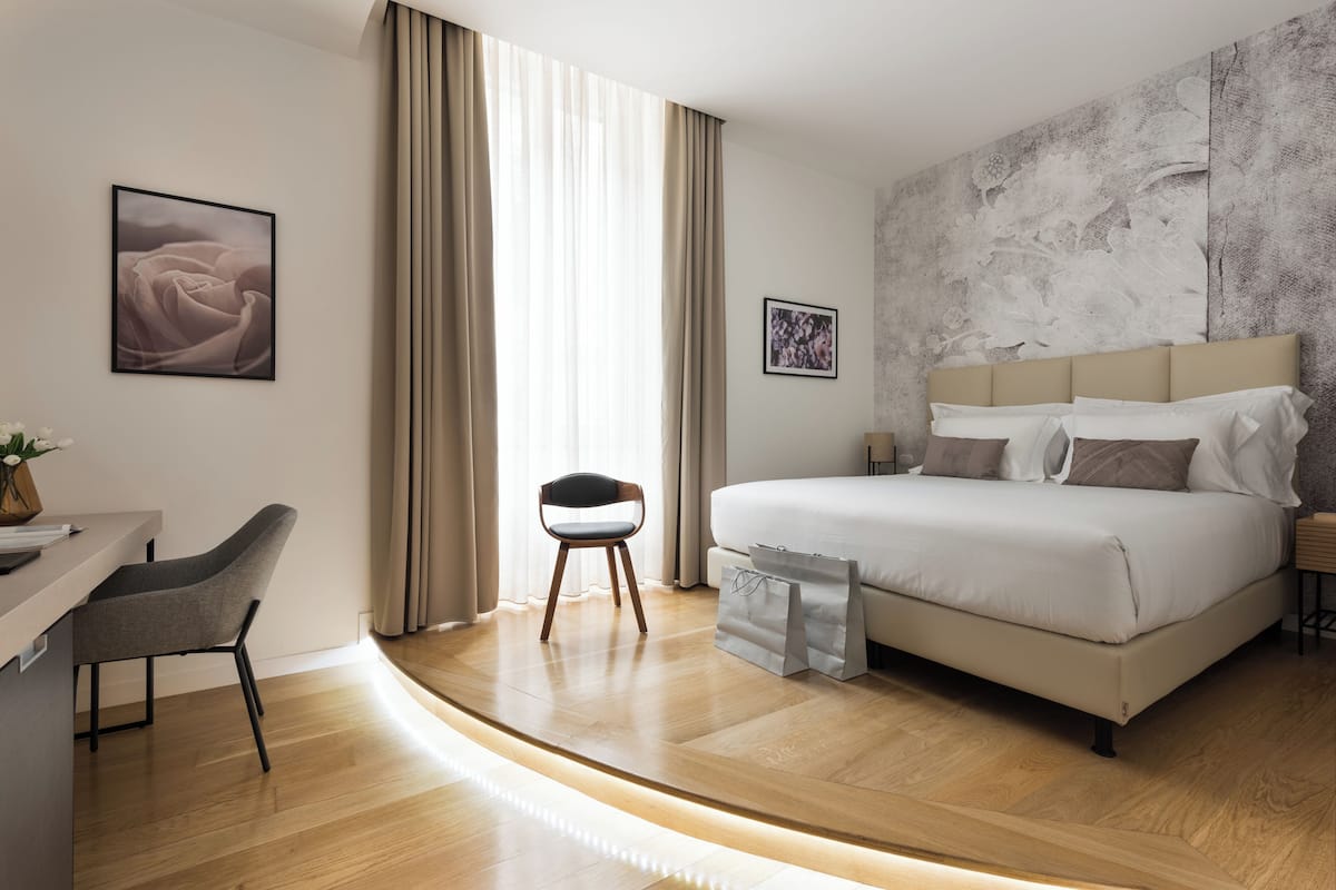 A modern hotel room with a bed, a desk, and a chair.